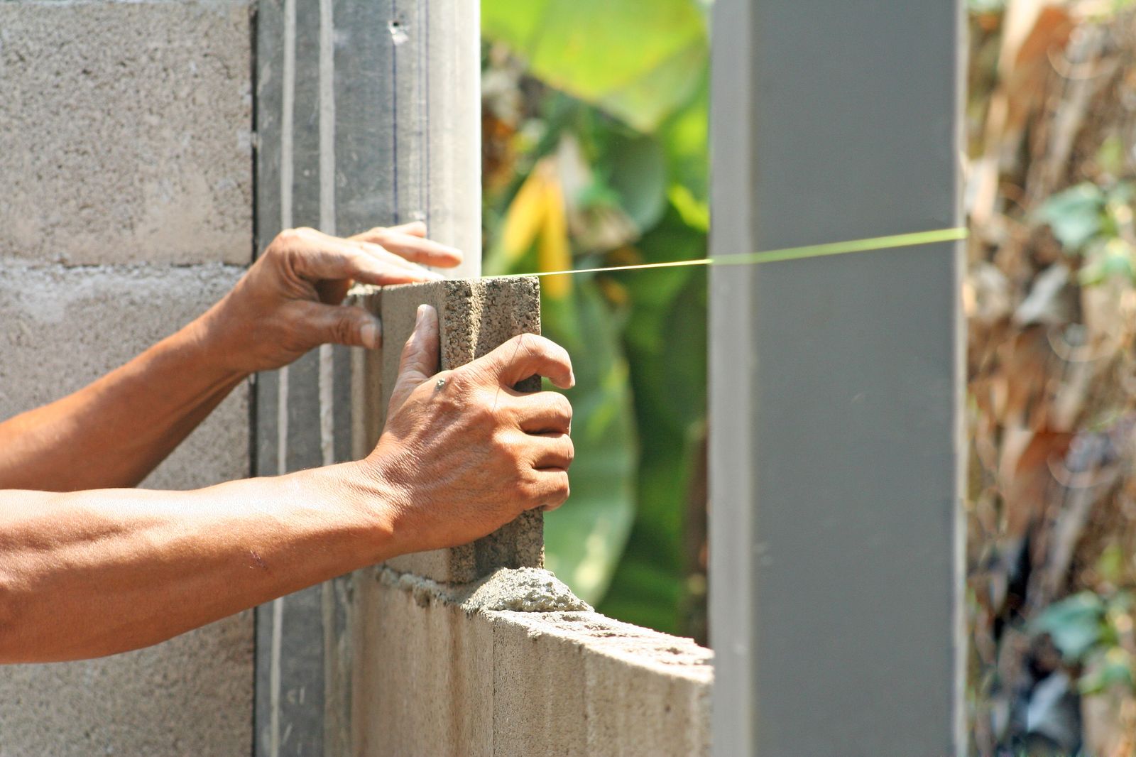 Mason setting a course of block to a string line
